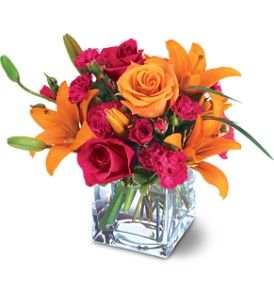 Lush colors, but it still manages to be elegant.  I really enjoy the clear square vase.  Flowers are orange asiatic lilies and roses, with hot pink carnations and roses.