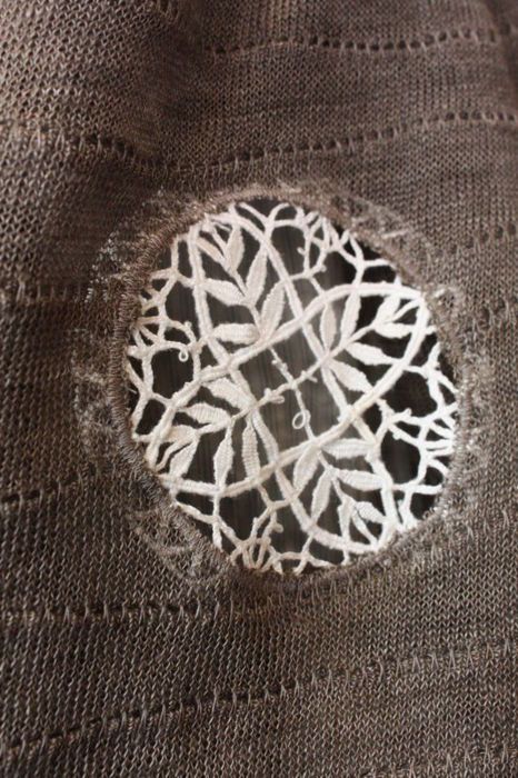 Using a piece of lace to mend a sweater.